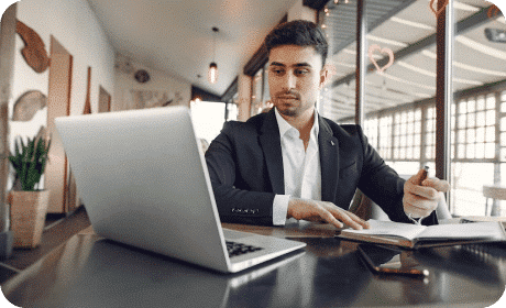 A man in a suit sitting at a table with a laptop.
