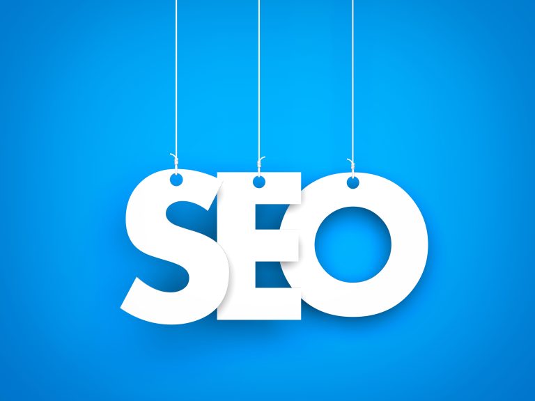 The word seo hanging from strings on a blue background.